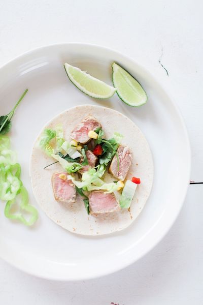 tuna tacos on white plate next to sliced lime