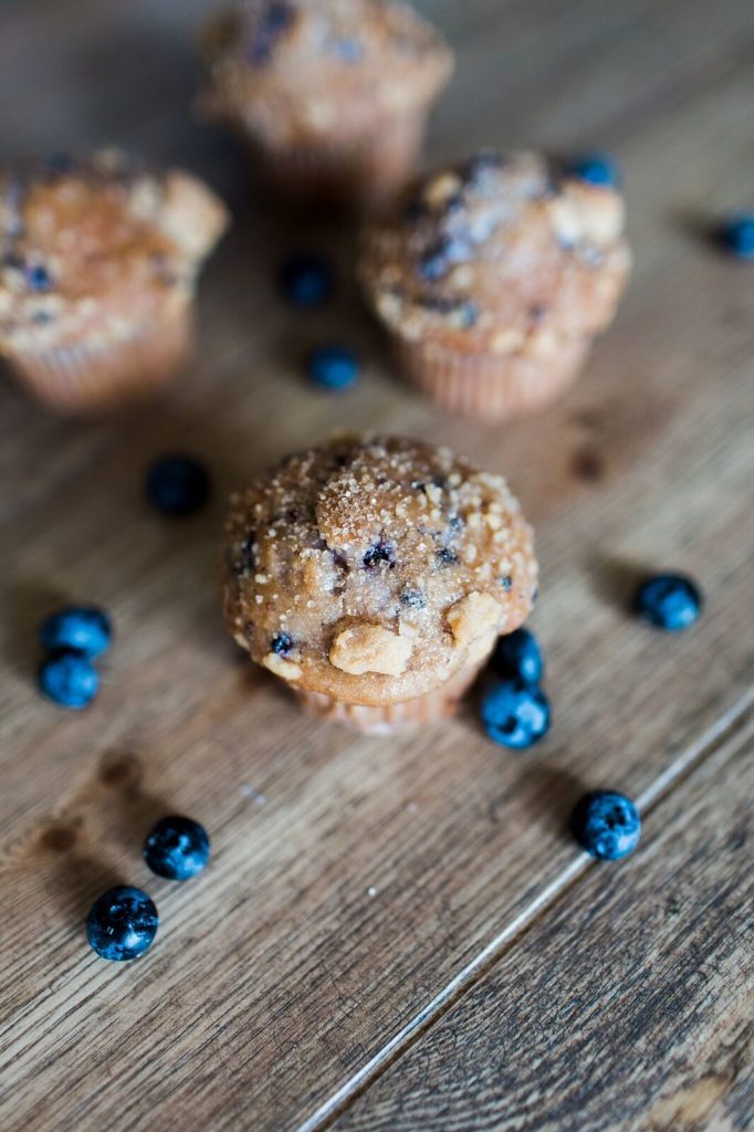 blueberry muffins on wood table with fresh blueberries