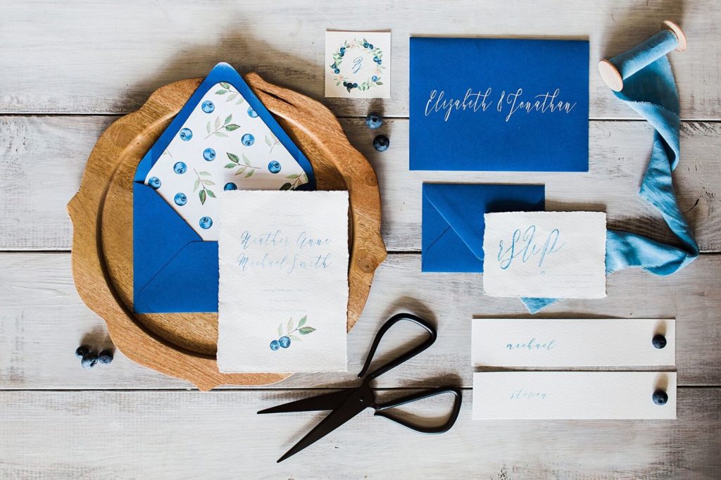 blueberry themed stationery and invitation suite on wood charger