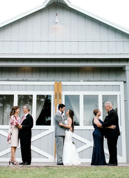 couples standing in front of boathouse doors 