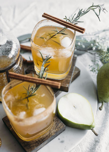 two pear and honey margaritas with cinnamon sticks and rosemary springs